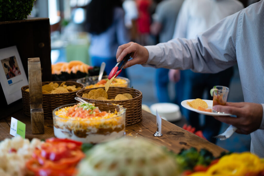 Person grabbing nacho chips and dip with tongs