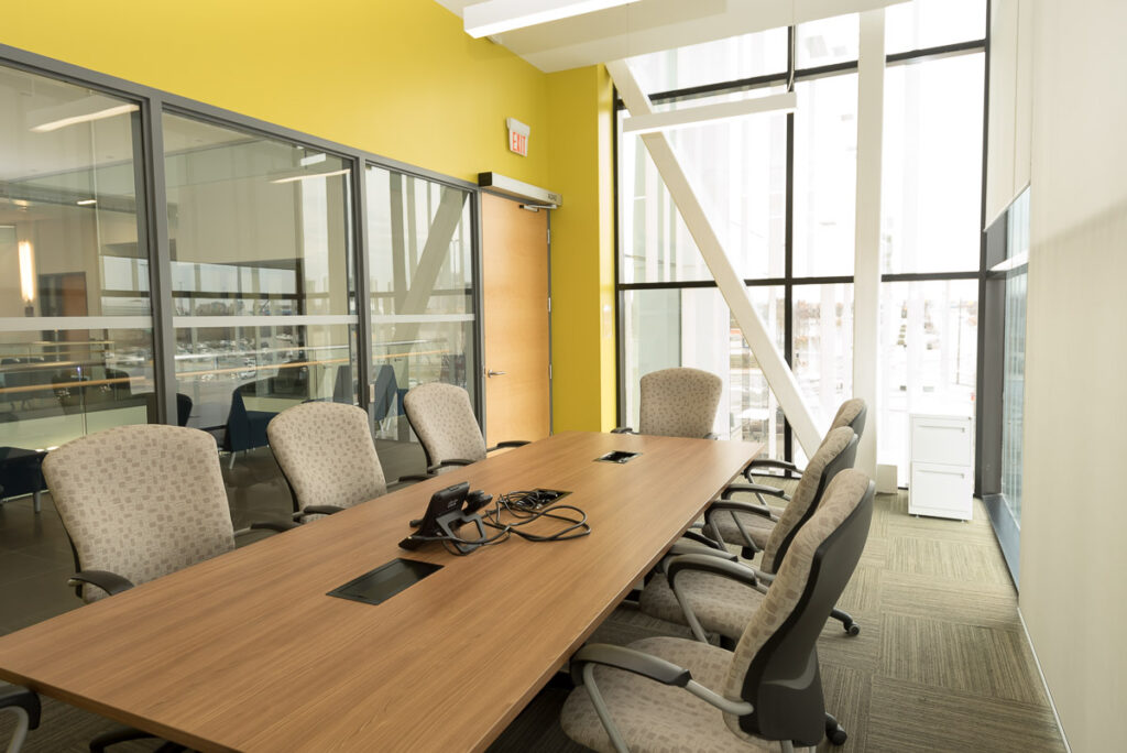 Empty boardroom with large windows and a long table and office chairs surrounding it