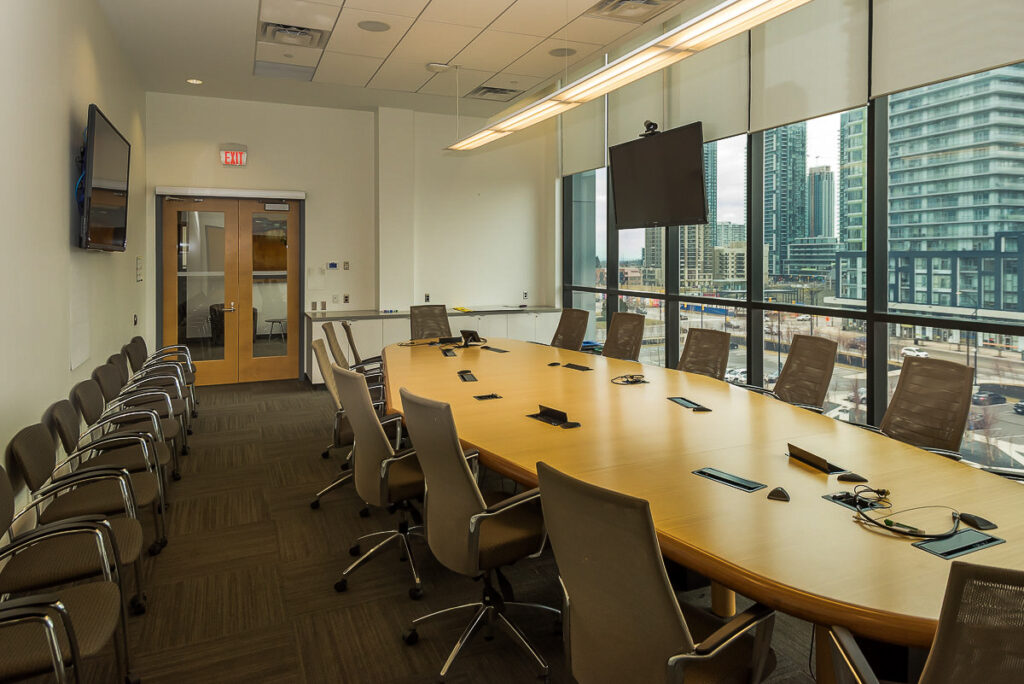 Boardroom with large wooden table surrounded by office chairs
