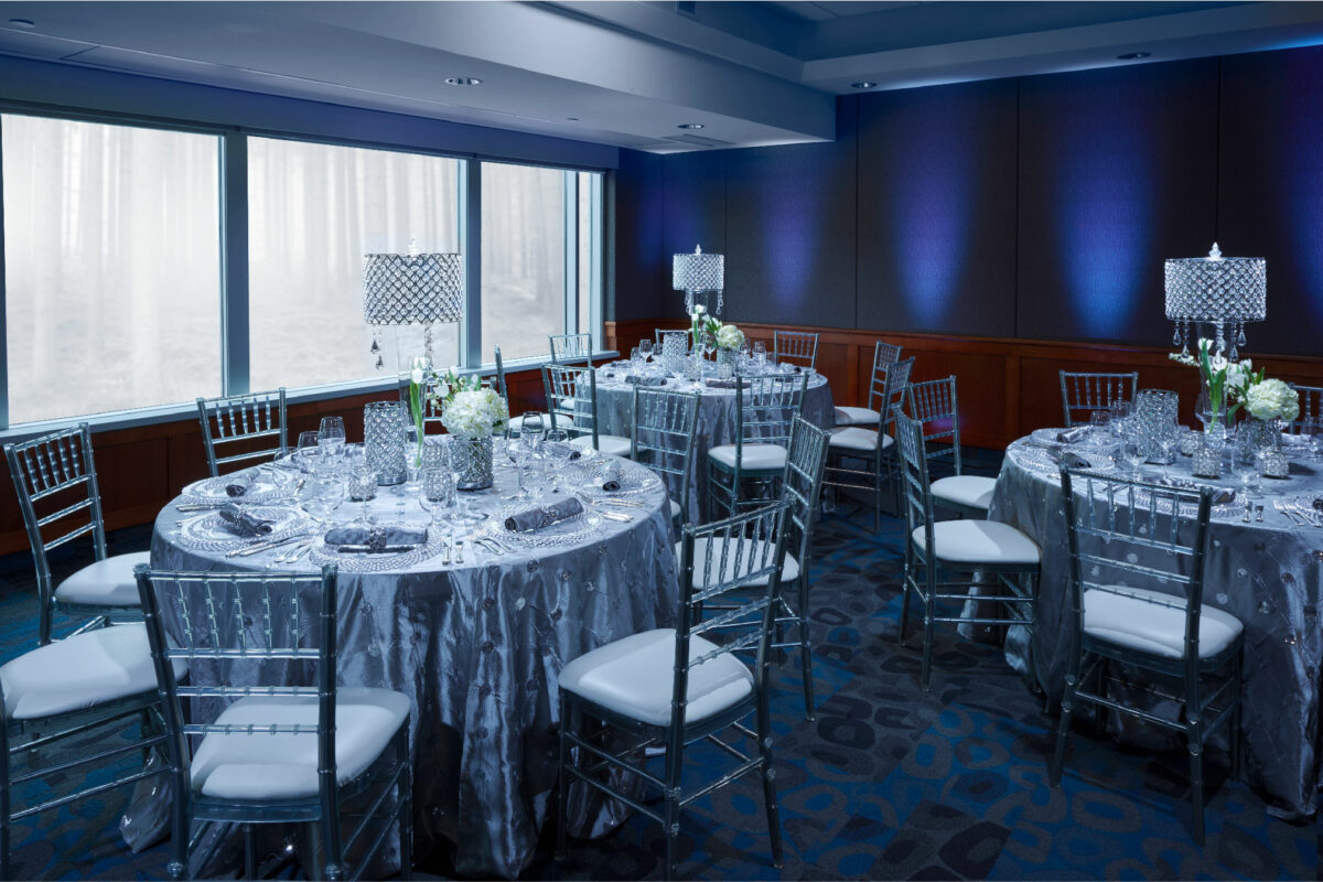 Three round tables with wedding decor and dinner sets with chairs seated around them