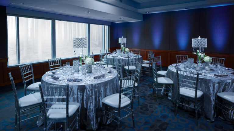 Three round tables with wedding decor and dinner sets with chairs seated around them