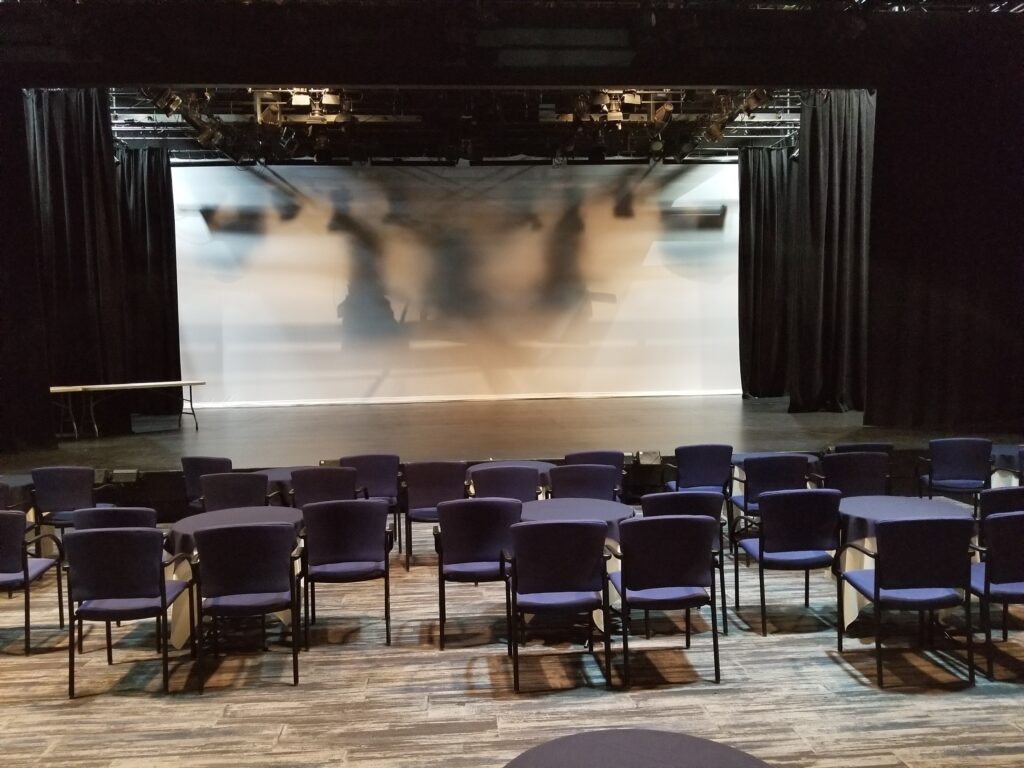 Blue chairs facing a light theatre stage