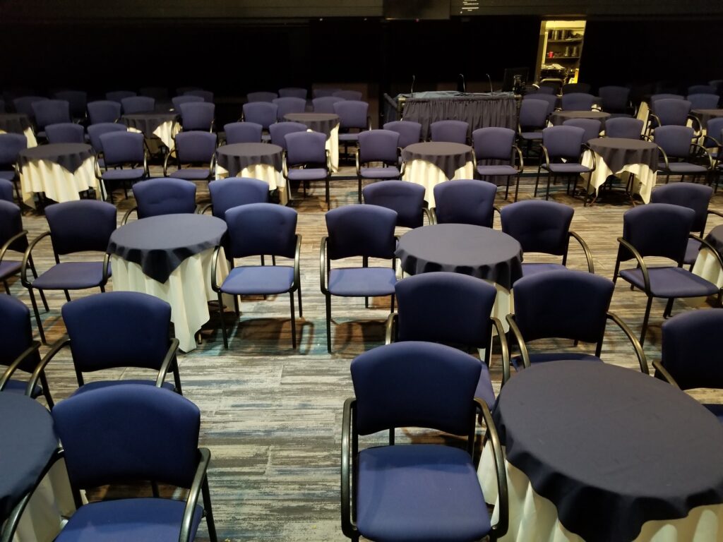 blue chairs cabaret style around round tables in a theatre